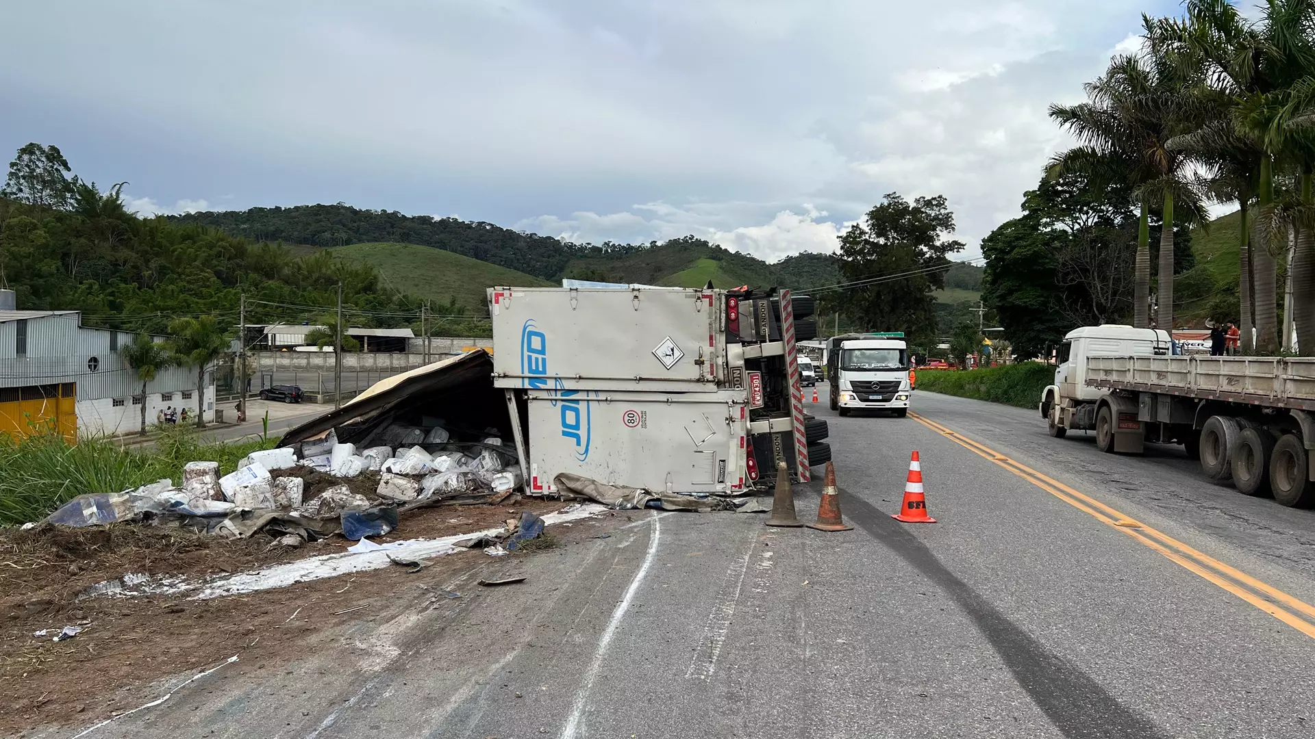 Carreta carregada com insumos agrícolas tomba na pista e atinge carro na BR-040 em Santos Dumont